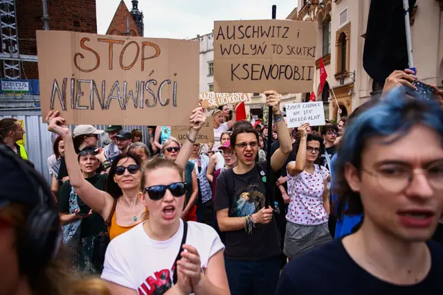 Люди держат плакаты во время контрманифестации, в то время как сторонники крайне правых политических партий участвуют в антииммиграционной акции протеста на Рыночной площади в Кракове, Польша, 19 июля 2025 года