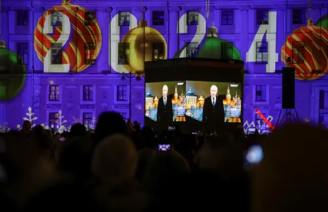年越しイベントのため広場に集まり、プーチン大統領による恒例の新年あいさつ映像を見る人たち（12月31日、サンクトペテルブルク）
