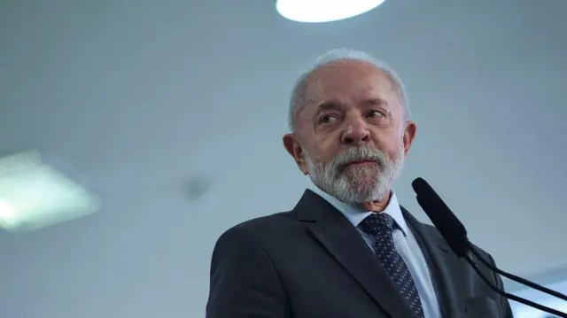 Lula com olhar preocupado, olhando para o lado diante de microfones