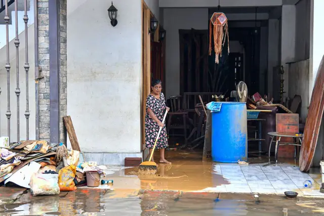 ගංවතුර තත්ත්වයෙන් පසු නිවෙස පිරිසිදු කරන කාන්තාවක්