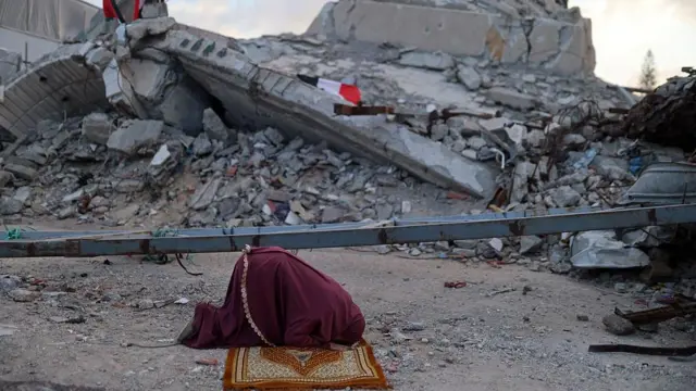 காஸா நகரில் இடிபாடுகளுக்கிடையே தொழுகை நடத்தும் முஸ்லிம் பெண் ஒருவர் 