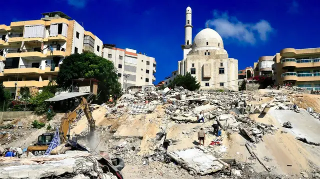Foto mostra pessoas em meio a escombros após um ataque.
