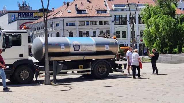 Cisterna za vodu u centru grada, oko nje ljudi