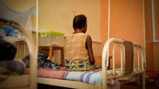 A patient with an advanced stage of AIDS sits on her bed at the community hospital in Bangui, in the Central African Republic.