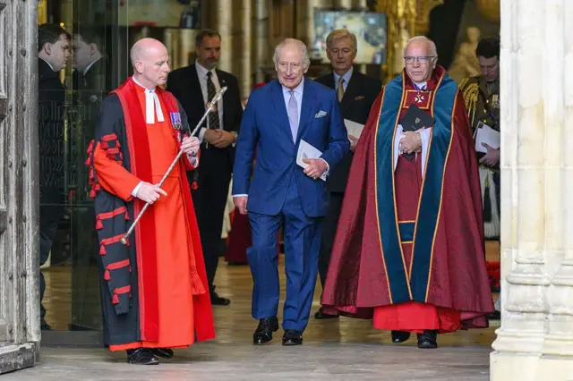 Король Чарльз у синьому костюмі стоїть біля священників 