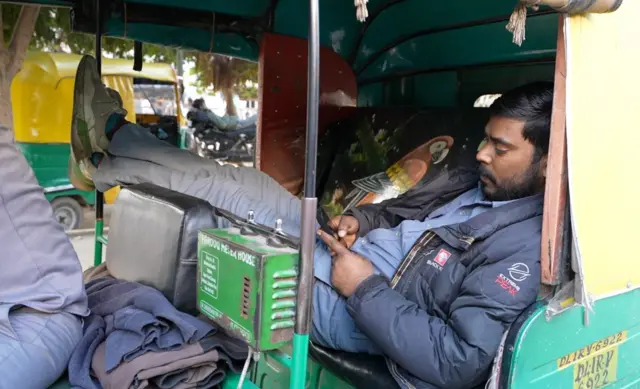 सवारी के इंतज़ार में ऑटो में सुस्ताता एक चालक