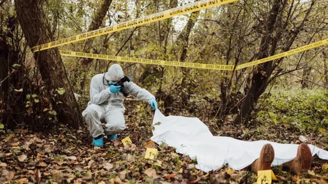 Seorang penyelidik berpengalaman di tempat kejadian perkara (TKP) sedang mengumpulkan bukti dan mengambil foto tentang bukti-bukti do lokasi hutan.
