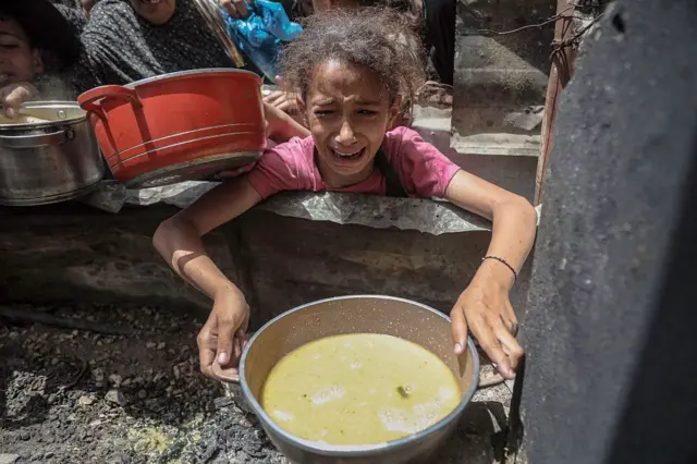 فتاة تحمل وعاءً للحصول على طعام  في مخيم جباليا للاجئين، مدينة غزة، غزة في 19 مايو/أيار 2025. 