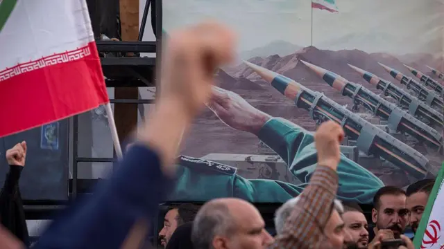 Zdjęcie pokazuje Irańczyków wykrzykujących na wiecu antyizraelskie hasła, stojących przed banerem, na którym widać rakiety typu ziemia-ziemia irańskiej produkcji.