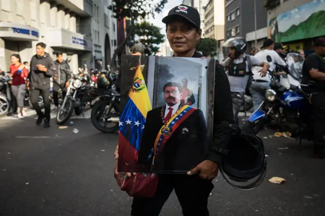 Uma pessoa segura uma imagem de Maduro