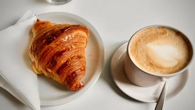 Zdjęcie klasycznego włoskiego śniadania: cappuccino i rogalika.