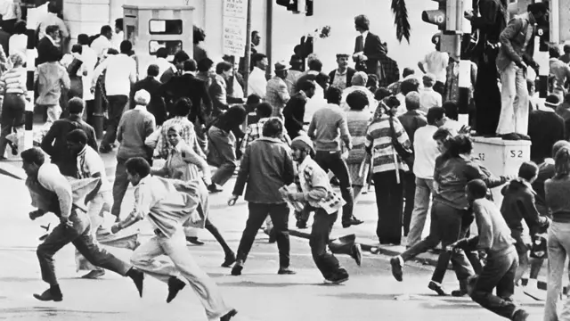 Mudaaharaadayaal ka cararaya booliis intii ay socdeen rabshado isir beegsi ah, oo ka dhacay magaalada Cape Town 1976dii.