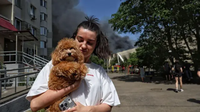 Дівчина тримає в руках собаку, рятуючись від російського ракетного удару по Одесі 24 червня 