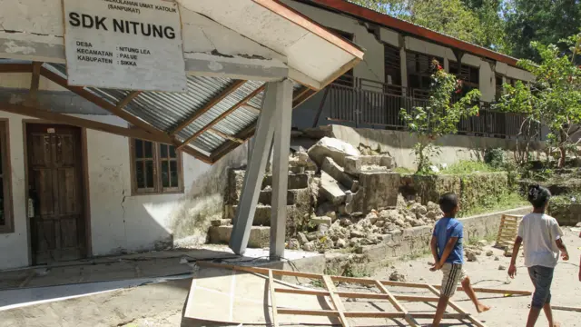Warga melintas di samping bangunan sekolah yang rusak akibat gempa bumi magnitudo 7,7 di Pulau Palue, Kabupaten Sikka, NTT, Rabu (19/8/2026)
