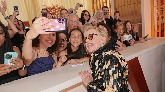 Жена са наочарима за сунце се слика са десетинама људи