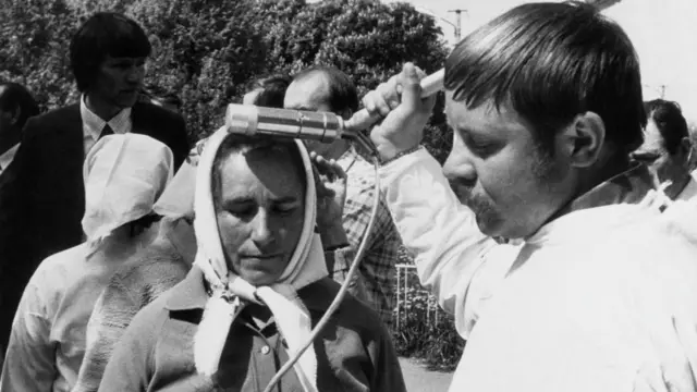 Евакуація людей після аварії на ЧАЕС. Жінку вимірюють дозиметром 