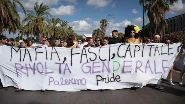 Orang-orang terlihat memegang spanduk meminta revolusi umum melawan mafia, fasisme dan kapitalisme.