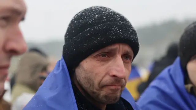 Повернений військовий у чорній шапці з українським прапором