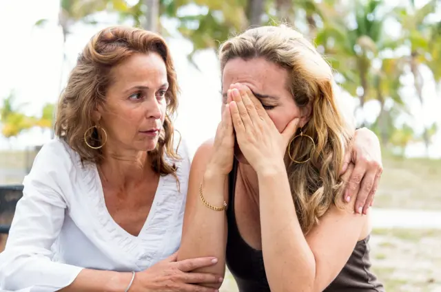 Una mujer abraza a otra que llora.