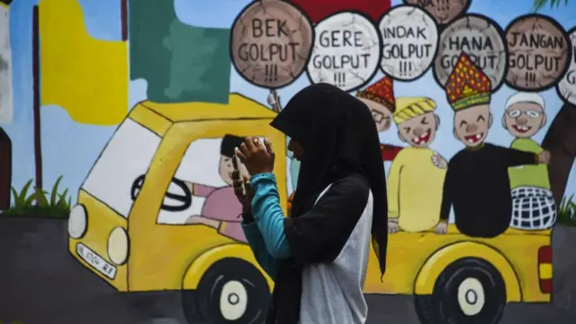 Foto ilustrasi pemuda di depan grafiti melarang golput