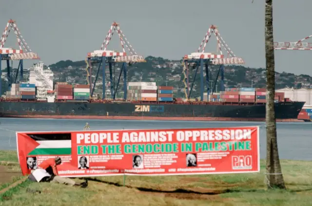 Bir afiş, arkada ZIM yük gemisi