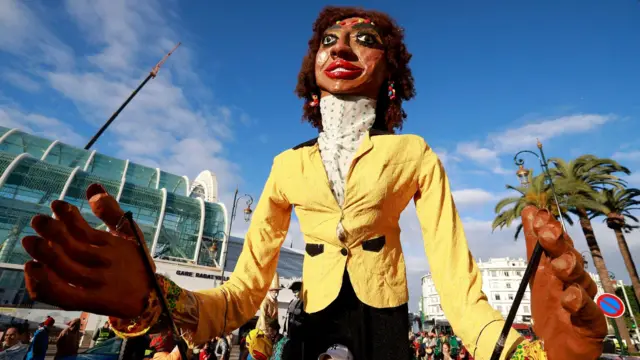 يتوجه المشجعون والفنانون في موكب إلى منطقة المشجعين في الرباط، المغرب، في 20 ديسمبر/كانون الأول 2025، قبل انطلاق بطولة كأس الأمم الأفريقية لكرة القدم. ويواجه منتخب المغرب منتخب جزر القمر في المباراة الافتتاحية يوم 21 ديسمبر/كانون الأول.