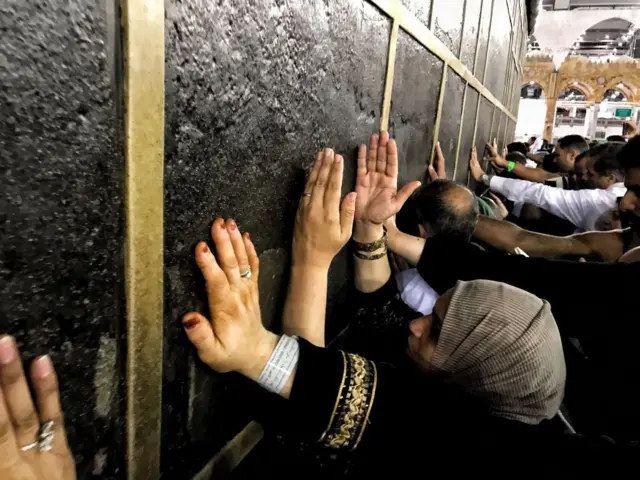 Des pèlerins musulmans effectuant le Hajj touchent la pierre de la Kaaba lors de leur circumambulation autour de la Kaaba, le lieu le plus sacré de l'islam, situé au centre de la Masjid al-Haram (Grande Mosquée) dans la ville sainte de La Mecque, en Arabie saoudite.