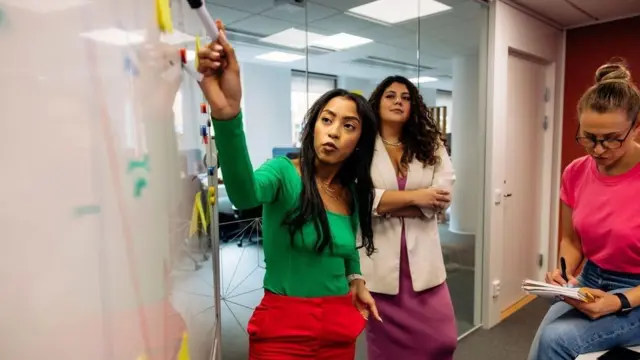 화이트보드 앞에 모여 회의하는 직원들의 모습