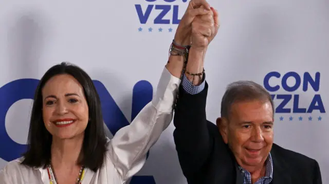La líder opositora venezolana, María Corina Machado, saluda con la mano al candidato presidencial opositor, Edmundo González Urrutia, en Caracas el 29 de julio de 2024, un día después de las elecciones presidenciales venezolanas.