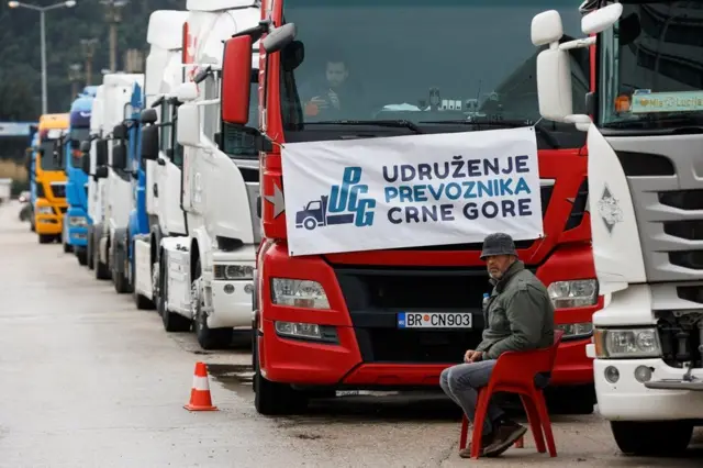 kamiondžije, crnogorski kamioni, crnogorske kamiondžije, vozač kamiona sedi pored desetine vozila parkiranih ispred Luke Bar
