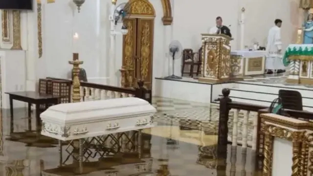 በጎርፍ በተጥለቀለቀው ቤተ ክርስቲያን ውስጥ የሬሳ ሳጥን ቁጭ ብሎ የቀብር ሥነ ሥርዓት እየተካሄደ