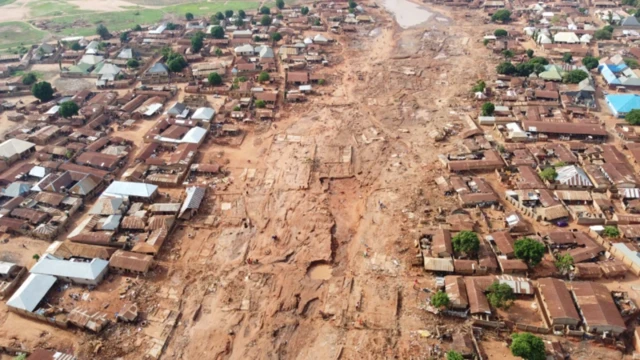 Clothes scata round, mattresses dey soaked wit water and different crushed metal roofing sheets show wia some of di dozens of houses bin dey bifor, for Tiffin Maza Community for Mokwa town, Niger state.