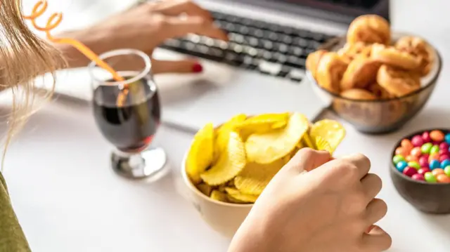 Pessoa comendo snacksslot 91frente do computador