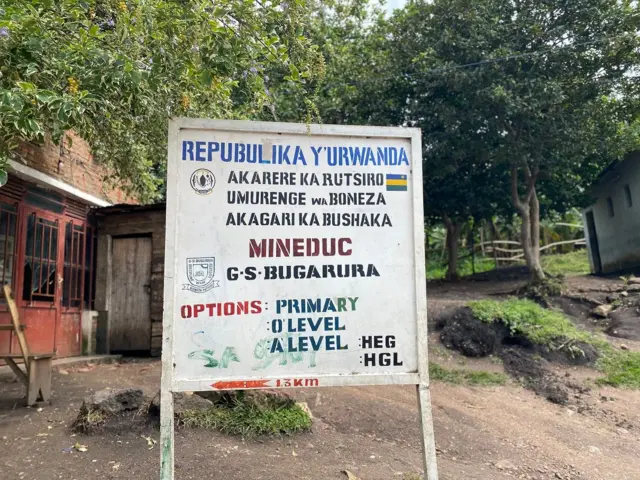 Icyapa gikoze mu cyuma gisize irangi ry'umweru, kiriho ibendera ry'u Rwanda. Cyanditseho mu nyuguti z'icyapa (nkuru) amagambo arimo nka Repubulika y'u Rwanda, akarere ka Rutsiro, umurenge wa Boneza n'akagari ka Bushaka. Kigaragaza intera ihari ngo ugere ku ishuri ryisumbuye rya Bugarura n'amashami yaryo kandi ko ririmo n'icyiciro cy'amashuri abanza. Inyuma y'icyapa hari inzu n'ibiti. 