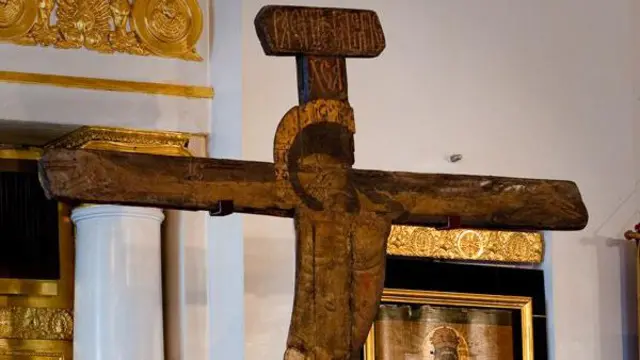 Древнее деревянное распятие на фоне икон 