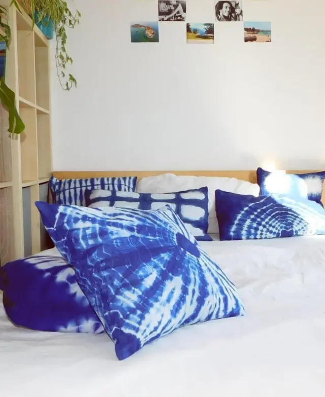Des coussins teints en bleu et blanc sur un lit avec un drap blanc