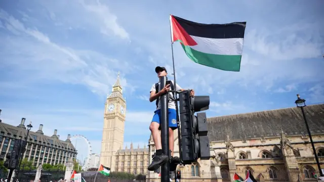 Человек с палестинским флагом на светофоре на площади в Лондоне