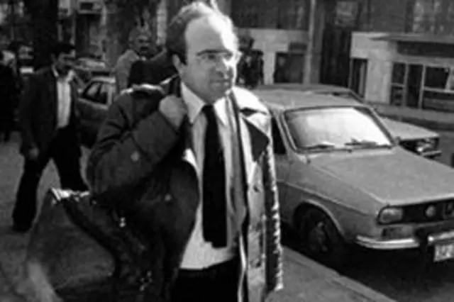 Uğur Mumcu çantasını sağ omzunda tutarak sokakta yürüyor. 