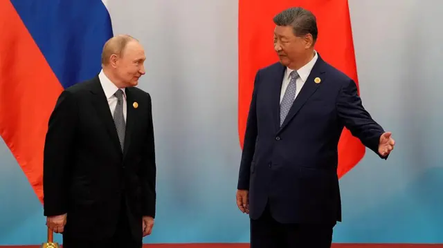 O Presidente chinês Xi Jinping (à direita) indica o caminho ao Presidente russo, Vladimir Putin em setembro de 2025, em Tianjin, na China