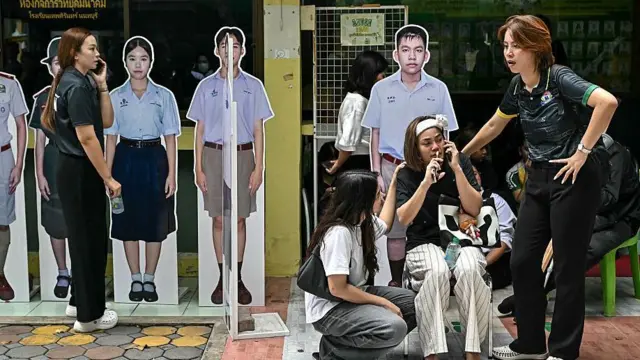 Dos mujeres asisten a otra en las afueras de un colegio en Thailandia.