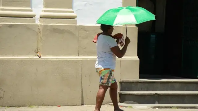 Mulher se protege do calor no Riosite de aposta com bônusJaneiro