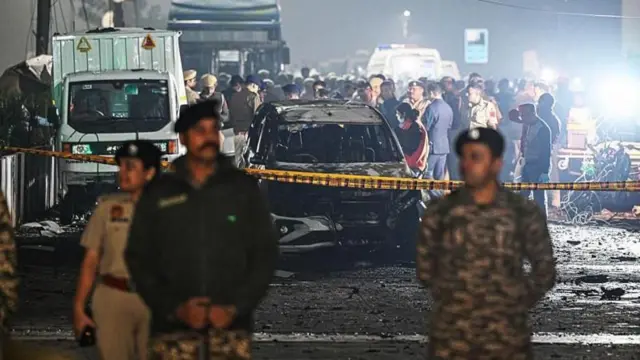 يو شمېر پولیس ښکاري چې لاره یې تړلې او تر شا یې د اوروژنې دوه سره ګاډي هم ولاړ دي. 
