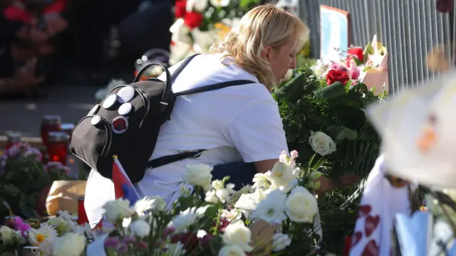 Dijana Hrka u beloj majici polaže cveće ispred Železničke stanice