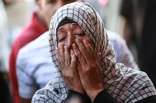 ग़ज़ा में इसराइली हमले में अपने परिजनों को खोने के बाद रोती एक महिला