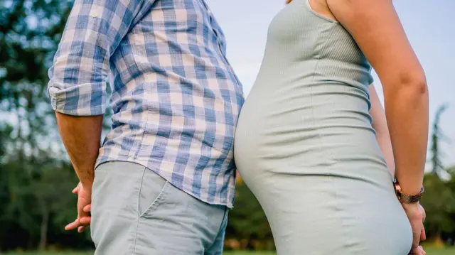 Un hombre choca su barriga contra la de una mujer embarazada.