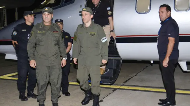 Nahuel Gallo (centro), vestido con su uniforme color verde militar, bajando del avión privado. A su lado ahy