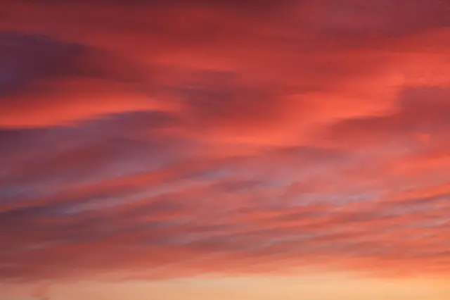 آسمان ابری که در غروب سرخ رنگ شده است