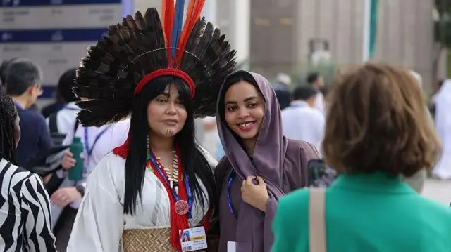 Uma mulher indígena brasileira da etnia Carajá tira uma foto com uma jovem durante a COP28