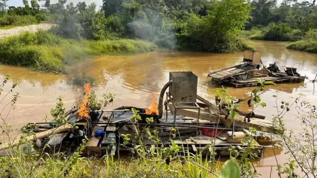 an illegal mining site with burnt equipment on the water body
