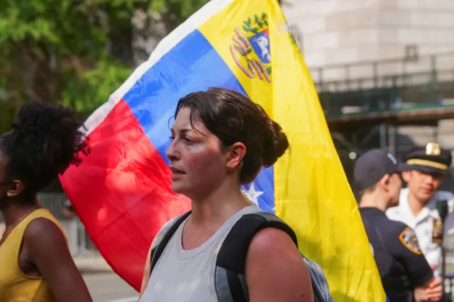 Una mujer junto a una bandera de Venezuela en una calle de Nueva York.